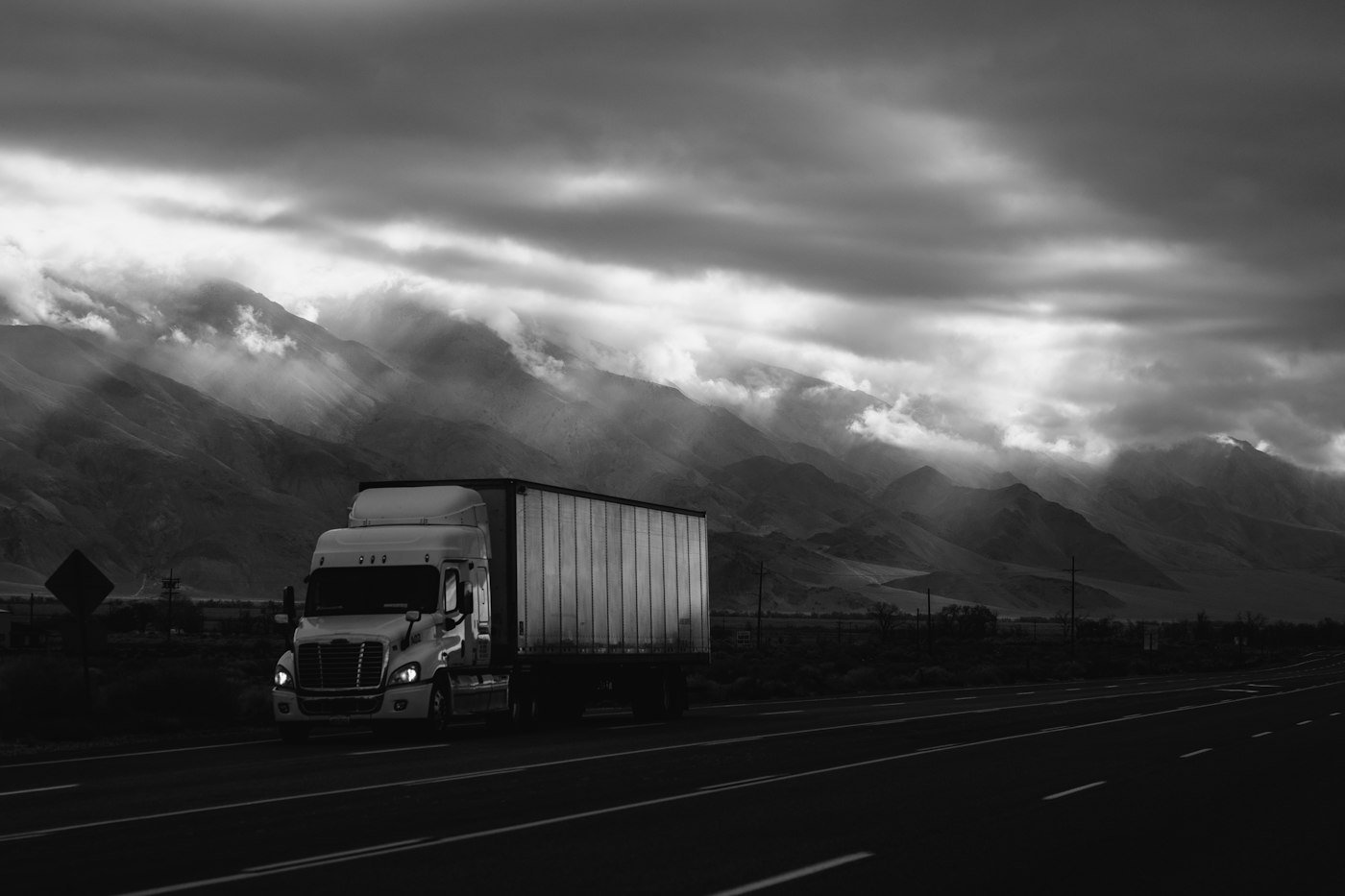 Tractor-trailer running beneath a dramatic sky